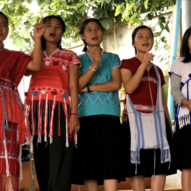 Five young women are shown performing on a stage in Thailand