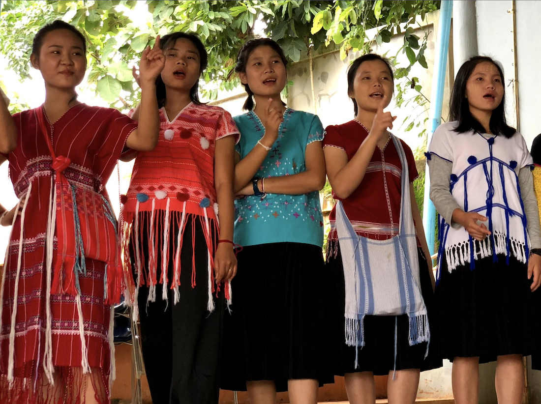 Five young women are shown performing on a stage in Thailand