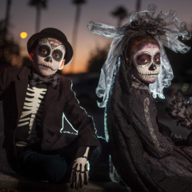 Two dark skinned young people dressed as skeletons at sunset