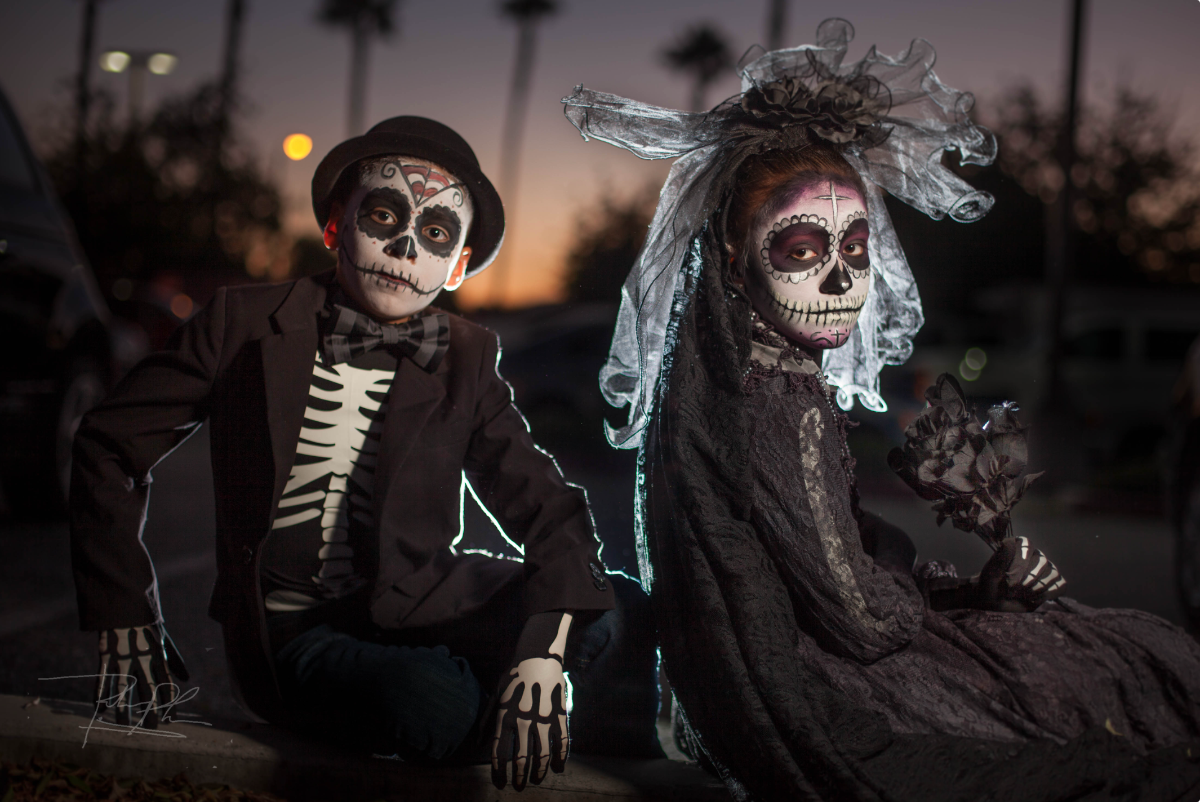 Two dark skinned young people dressed as skeletons at sunset